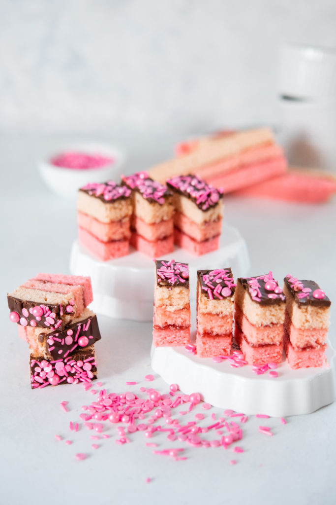 Italian pink rainbow cookies topped with chocolate and pink sprinkles